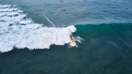 Aerial view of a surfer riding on the waves in the ocean