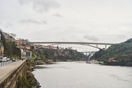 Porto, Portugal - 12.25.2022: A scenic view of a river, a beautiful bridge, and picturesque hilltop houses nearbyのeditorial素材
