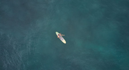 Aerial view of the ocean and surfer girl.