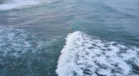 Aerial view of a surfer riding on the waves in the ocean