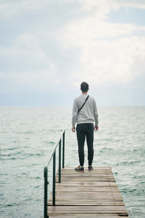 A young man admires the lake. View from the backの写真素材