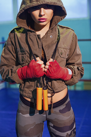 Portrait of female boxer in sport wear with fighting stance against spotlight. Sexy fitness blonde girl in sport wear with perfect body posing in boxing gym. Sport, fitness, lifestyle conceptの写真素材