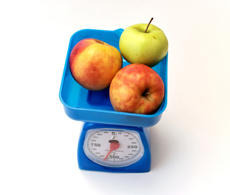 Two red and one green Apple on table scalesの写真素材