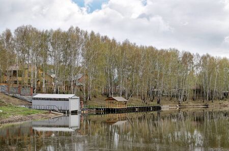 The house and metal building on the banks of the river in the springの写真素材