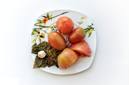 Pickled tomatoes with leaves of currant on a plate-top viewの写真素材