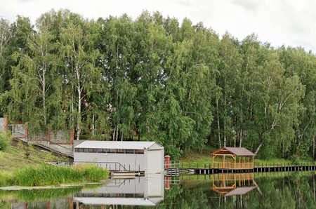 Wood and metal shed on the pond in the summerの写真素材