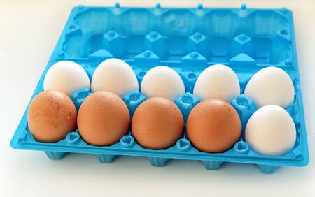 Eggs are white and yellow in the open blue plastic container closeupの写真素材