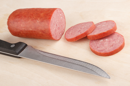 smoked sausage sliced on a chopping board with a knifeの写真素材
