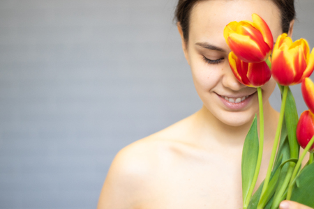 Beautiful girl with flowers tulips in hands on a light background.の写真素材