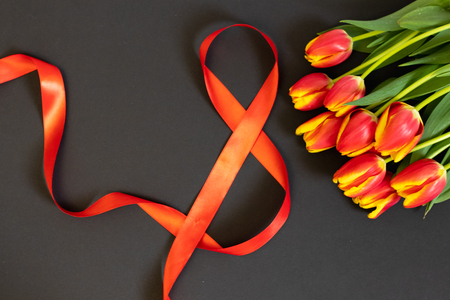 Background with flowers tulips and 8 ribbon on black background.の写真素材