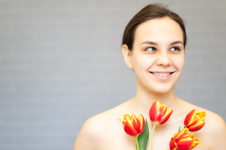 Beautiful girl with flowers tulips in hands on a light background.の写真素材