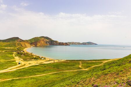 Sunny weather over a field with hills near the sea.の写真素材