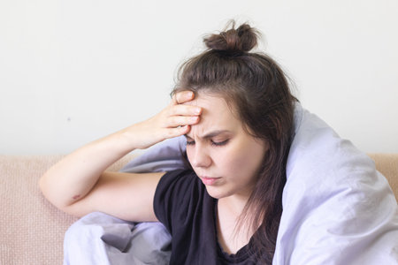 Sick young woman sitting at home with severe headacheの写真素材