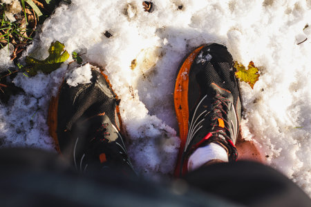 A man in running shoes stands in the snow