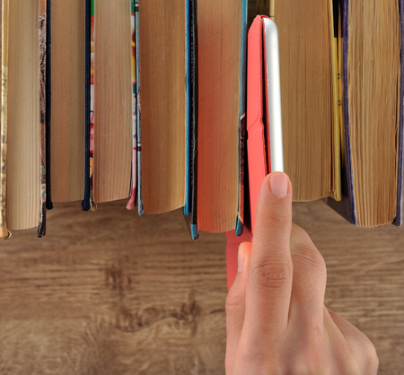 Hand taking tablet from bookshelfの写真素材