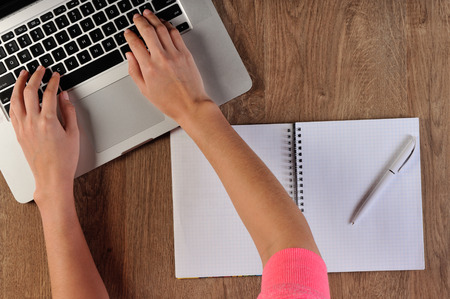 person writing in notebook infront of laptopの写真素材