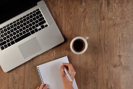 person writing in notebook infront of laptopの写真素材