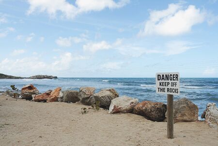 sign on beach with Danger keep off the rocksの写真素材