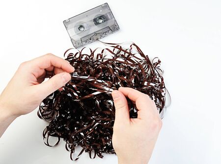hands uncurving audio tape on white backgroundの写真素材