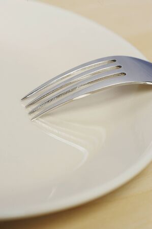 close up of empty plate on wood table with forkの写真素材