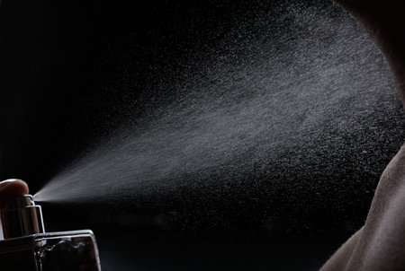 spray perfume on men body black background