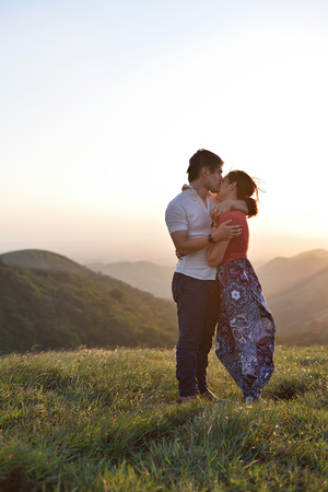 couple hugging stand in gold grass during sunsetの写真素材