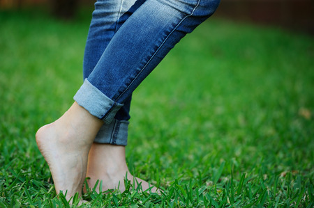 woman bare feet in jeans on park green grassの写真素材