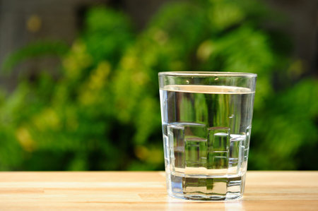 glass full of water  in green garden background