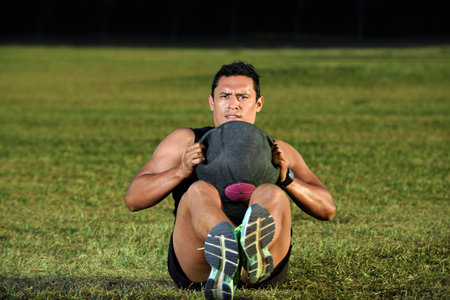 man workout on green grass with heavy ball