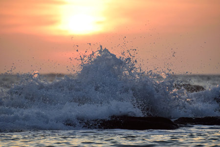 close up of sea water splash on rocks sunset background