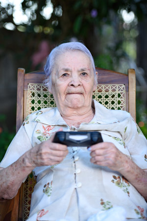 grandma holding joystick and playing games outside