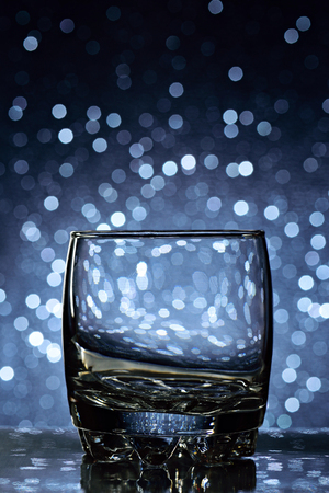 empty whisky glass on blue blurred backgroundの写真素材