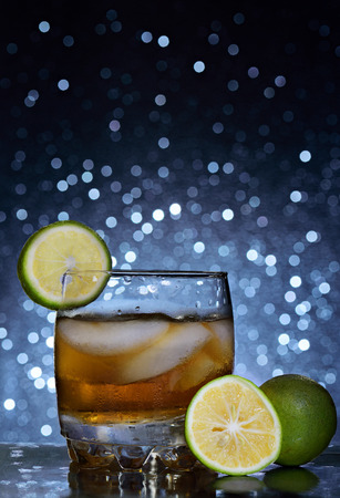 glass whisky and ice, lemon ob blurred backgroundの写真素材