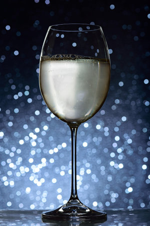 long glass with white wine on blue bokeh backgroundの写真素材