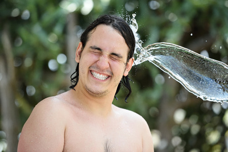 water splash hit man head on blur green backgroundの写真素材