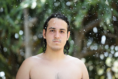 young man in water splashes on blur green backgroundの写真素材