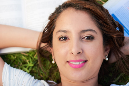 woman laying on her back with books on the groundの写真素材
