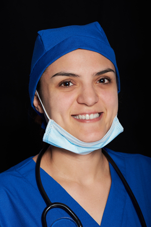 doctor smiling on a black background and with mask on her neckの写真素材