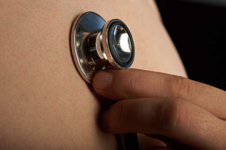 close up of hand with stethoscope next to chestの写真素材
