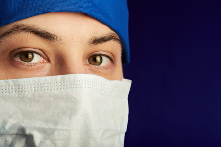 close up of doctor in mask isolated on purple