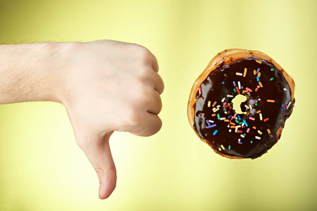 hand show thumb down to donut isolated on yellow