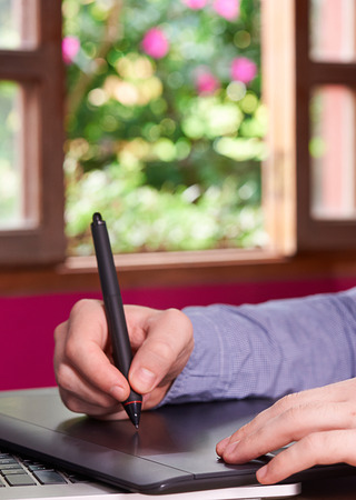 man working on designer tablet with open windowの写真素材