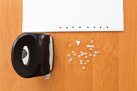 Hole puncher with paper and confetti on the office tableの写真素材