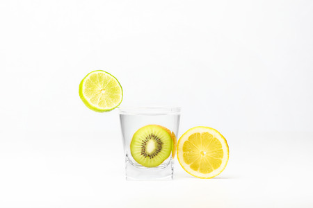 Kiwi in the glass of water, piece of lemon and lime isolated on white backgroundの写真素材