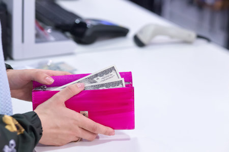 Money in wallet in woman hands next to cashier