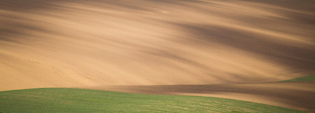 Brown cultivated wide field with shade from cloudsの写真素材