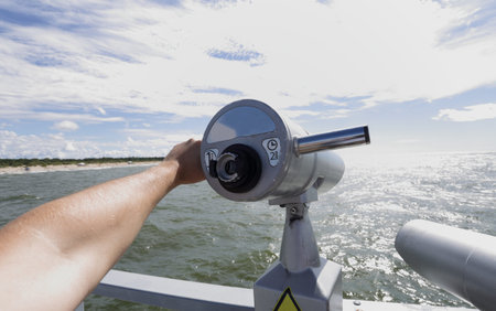 Telescope in hand towards to coast of seaside