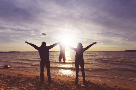 Happy family with a baby at the sunset hold hands