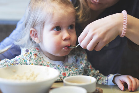 Mother feeding porridge her child with healthy breakfastの写真素材
