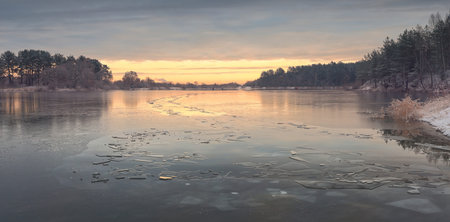 Autumn sunrise above frozen lake. First transparent ice covering lake.の写真素材